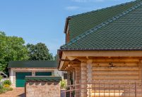 Seitliches Detail eines Holzhauses mit Biberschwanzziegel in der Farbe tannengrün auf dem Dach