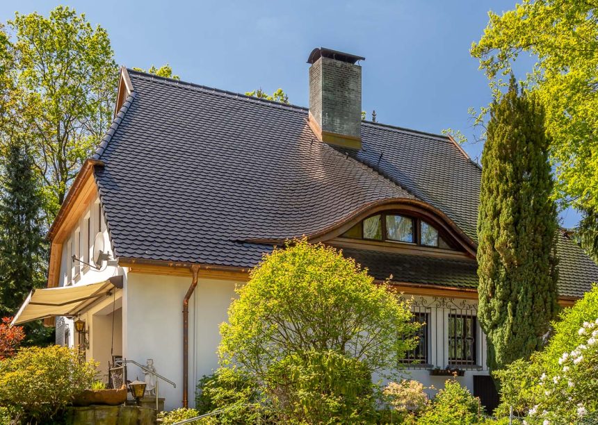 Traditionelles Einfamilienhaus mit Krüppelwalmdach, gedeckt mit Biberschwanzziegel in edelschwarz