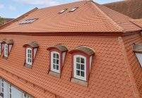 Mehrfamilienhaus mit Bibern in Rautespitz im traditionellen naturrot gedeckt mit Fokus auf die kunstvollen Gauben