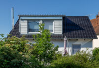 Klassisches Einfamilienhaus mit holzvertäfelter Gaube und J11v-Dach in edelschwarz.